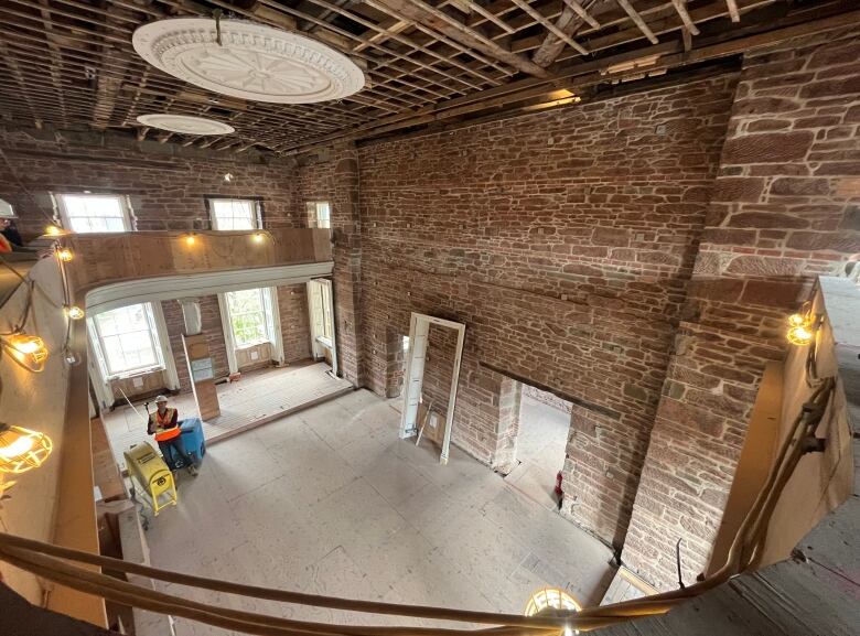 An interior shot of a large rotunda with red-brown stone walls and a large plaster medallion on the ceiling. 