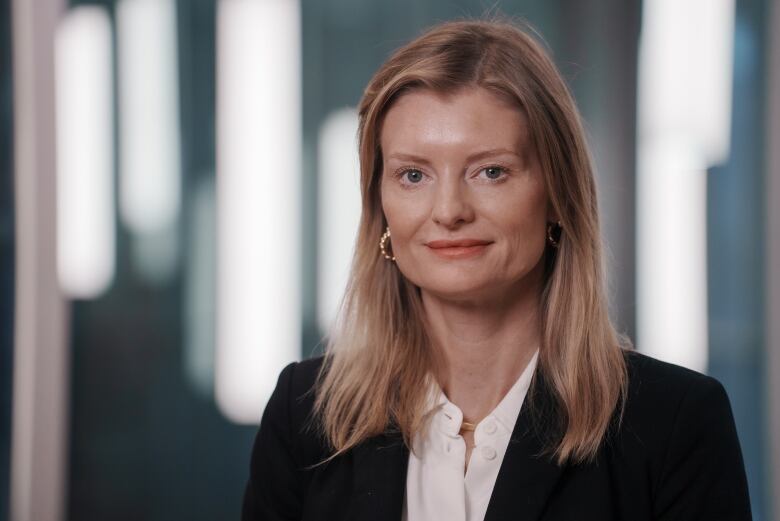 Blonde woman in a black blazer and white blouse. 