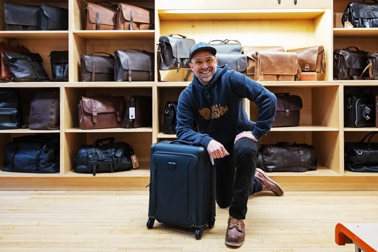 A man kneeling with a piece of luggage.