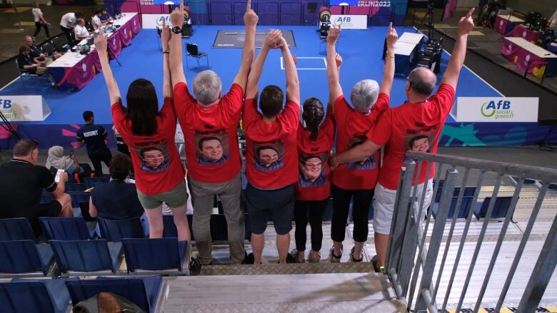 A group of people wear red shirts with a man's face on it, and the words 