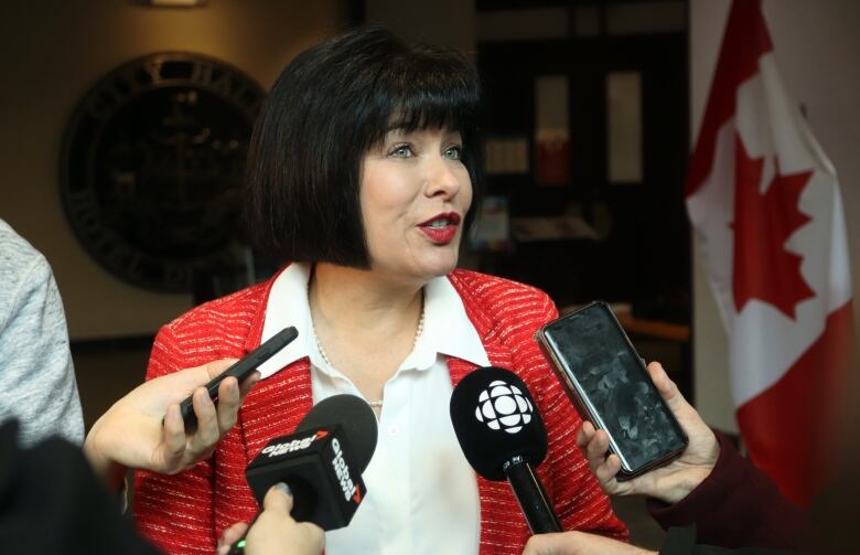 A woman speaking with various microphones in front of her. 