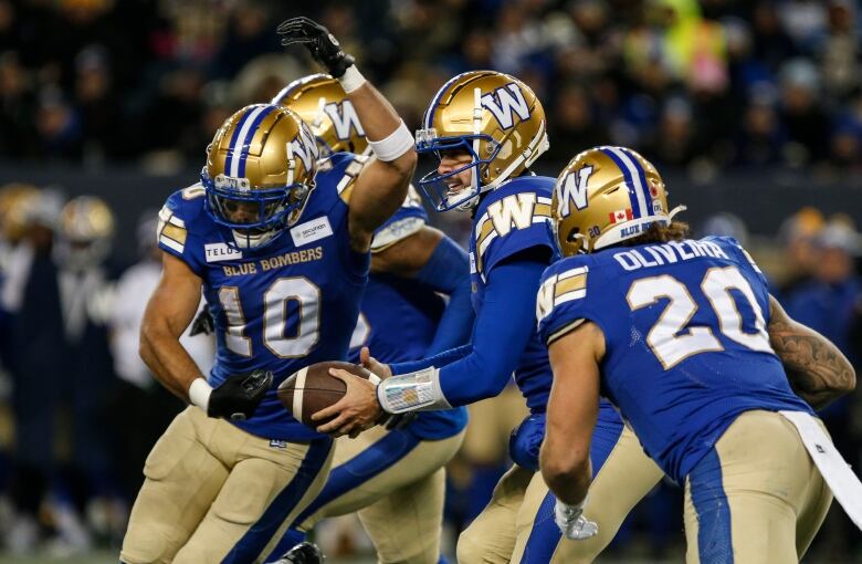 Four football players in blue and gold uniforms midplay.