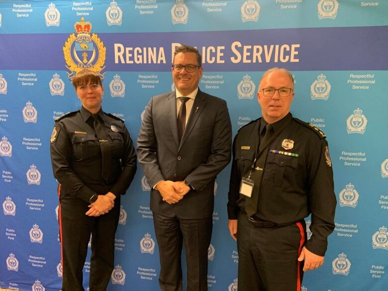 The officials stand in front of a Regina Police Service backdrop. 