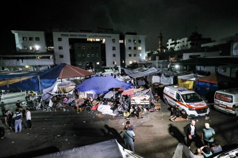 People camp outside a hospital at night.