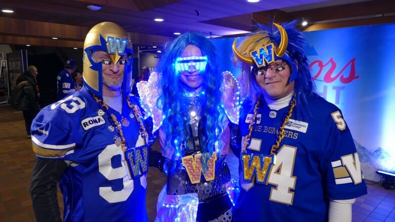 Three people in a room, decked out in Winnipeg Blue Bomber gear