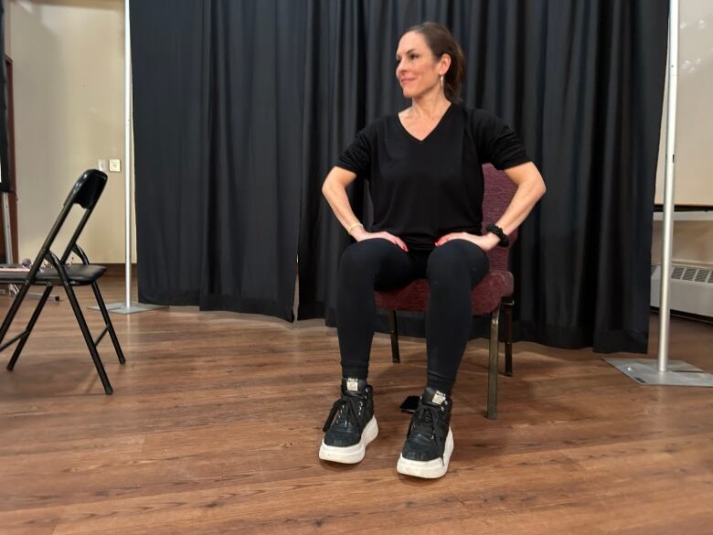 Woman in black sitting on a chair.