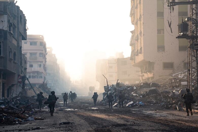 Soldiers walk through rubble