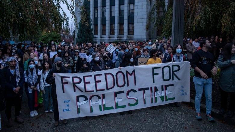 Large group of people holding a sign that says 'Freedom for Palestine'.