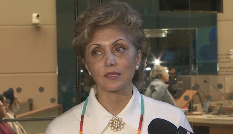 A woman speaks to reporters. 