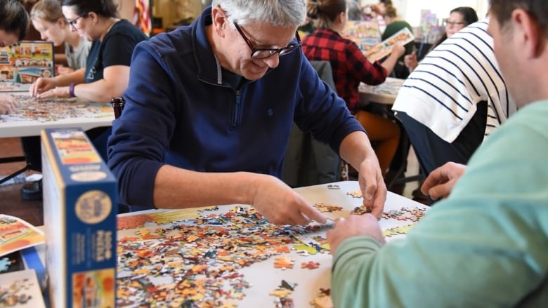 Two men do a jigsaw puzzle.