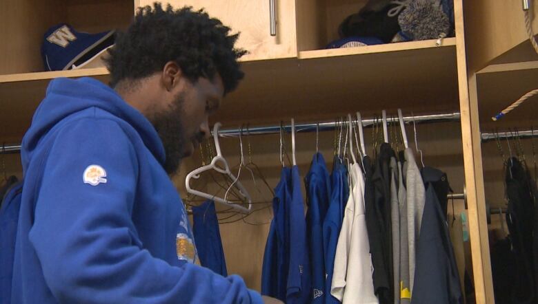 A football player in blue cleans out a locker.