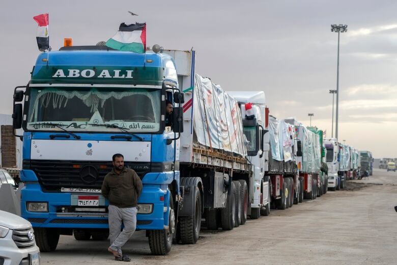 A line of transport trucks with tarps covering the cargo on the flatbeds/