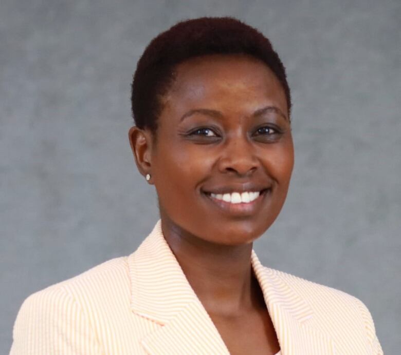 A woman wearing a light-coloured blazer poises for a photo.