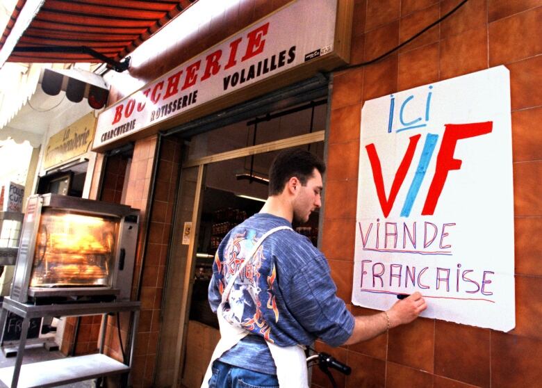 A butcher finishes a poster with the letters VF for 