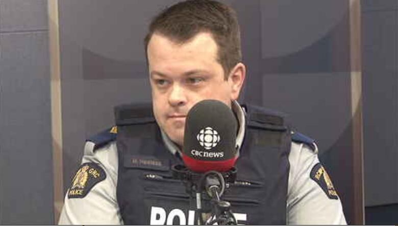 Man in police uniform sits at microphone.