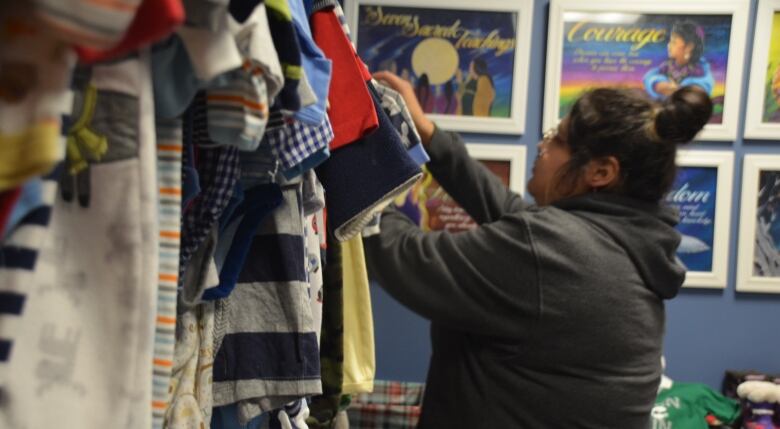 A woman looks through a rack of clothes 