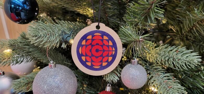 A 1970s CBC logo as a wooden Christmas tree ornament hangs on a tree