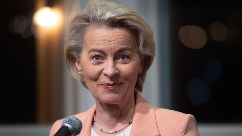 A woman with short grey hair wearing a beige blazer and a white shirt.