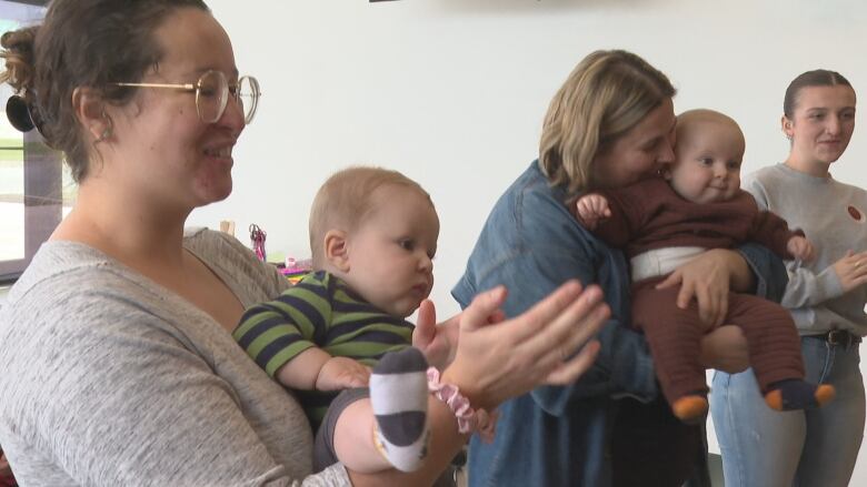 Mothers and children clap to a song.