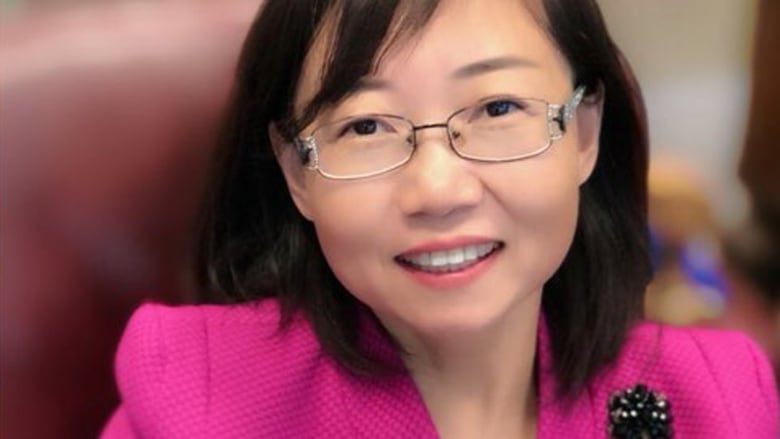 Hong Guo, a smiling East Asian woman wearing a pink blazer and glasses, is shown in a headshot.