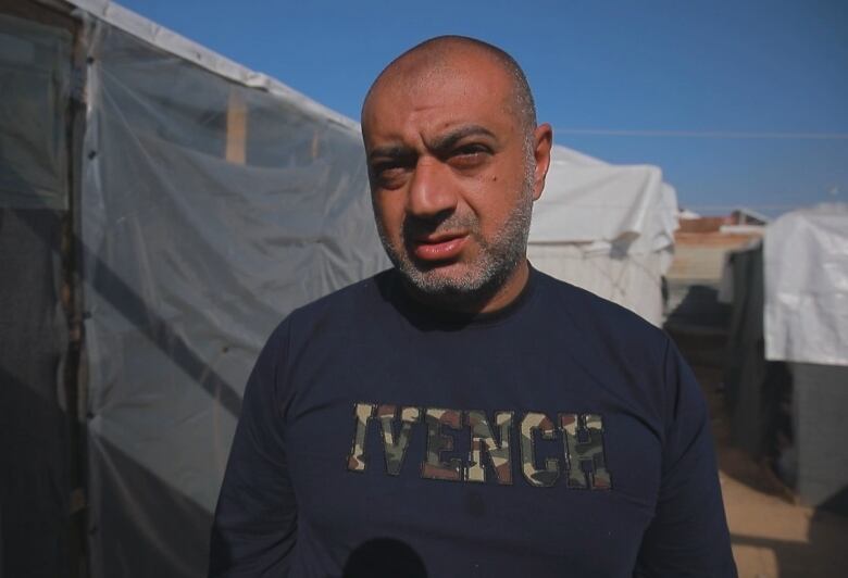 A man stands in front of tents.