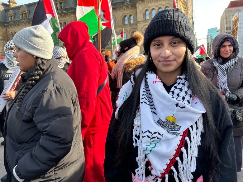 A woman with a scarf stands in a crowd.