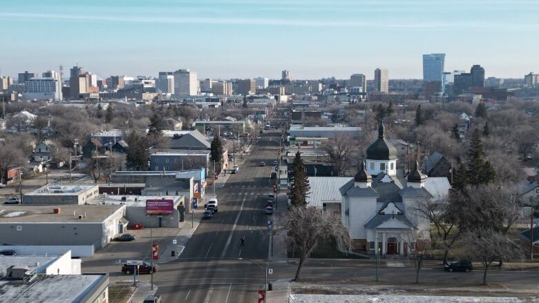 Aerial view of a neighbourhood in Saskatoon which includes a church, several businesses lined up along a thoroughfare street. 