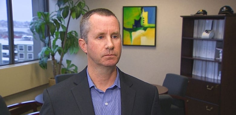 Man in blue blazer standing in office.