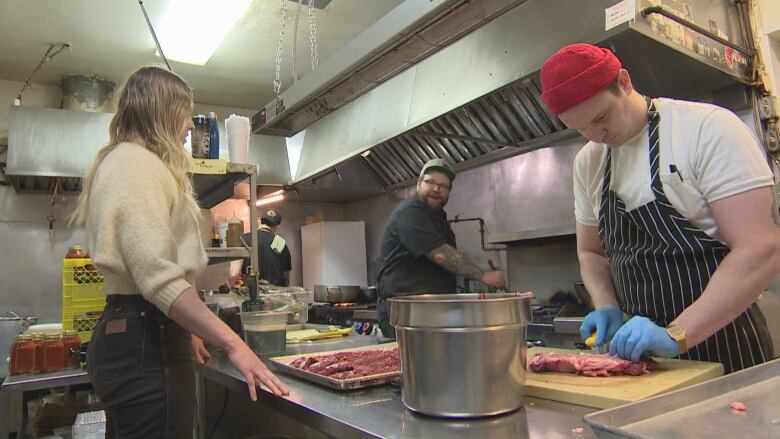 Four people work in a commercial kitchen.