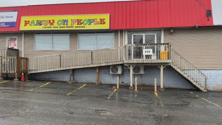 A strip mall style building with a metal red corrugated roof is shown with the sign 'Party On People'.