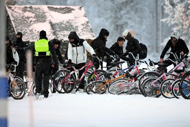 A group of people with their bicycles resting on the snowy ground.