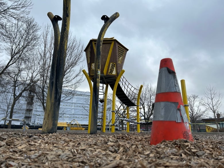 A playground that is partially burned with an orange cone in front of it. 