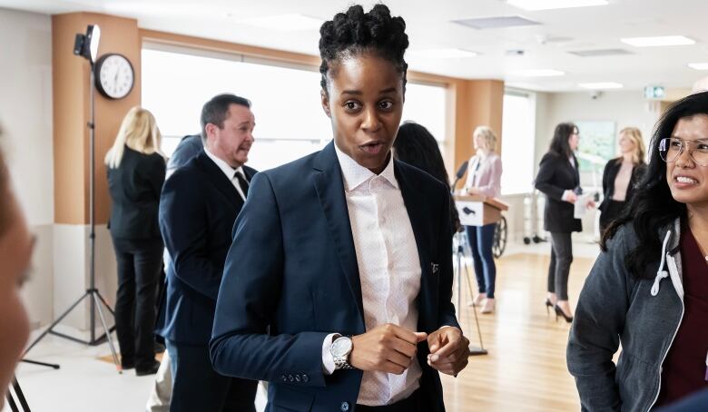 A person in a suit is shown speaking to health care workers.