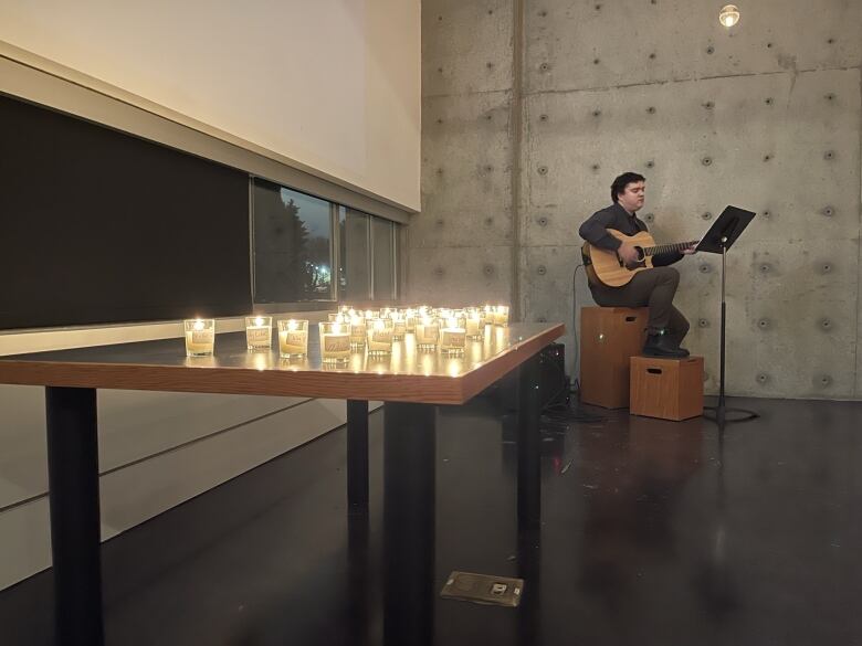 A candlelight vigil honours the lost loved ones of attendees at the Vancouver Hospice Society's Coping Through the Holidays event. Music Therapist Joshua Denny-Keys sings during the gathering.