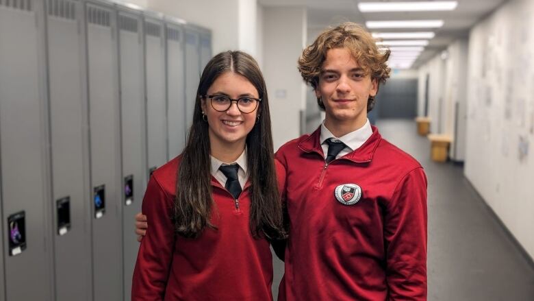 Two students in red uniforms pose for a photo. 