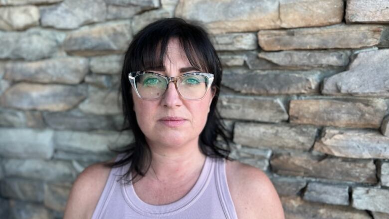 A woman wearing a tank top has a neutral expression on her face.