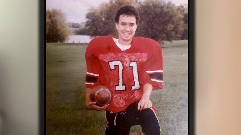 A man poses with a football. 