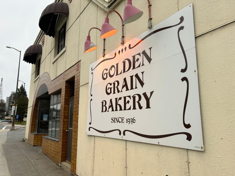 The front of a beige building with a sign that says Golden Grain Bakery.