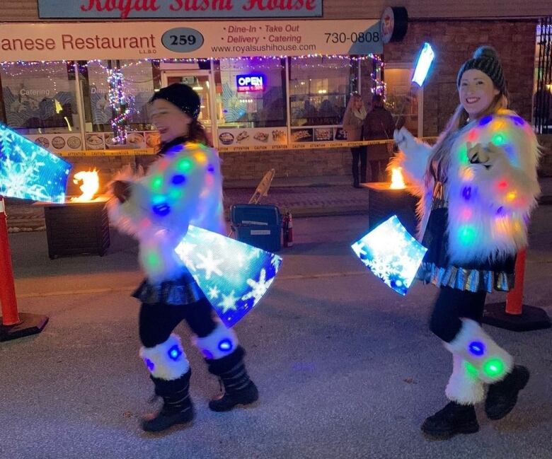 Two outdoor party-goers wear clothes and items that light up in the dark.