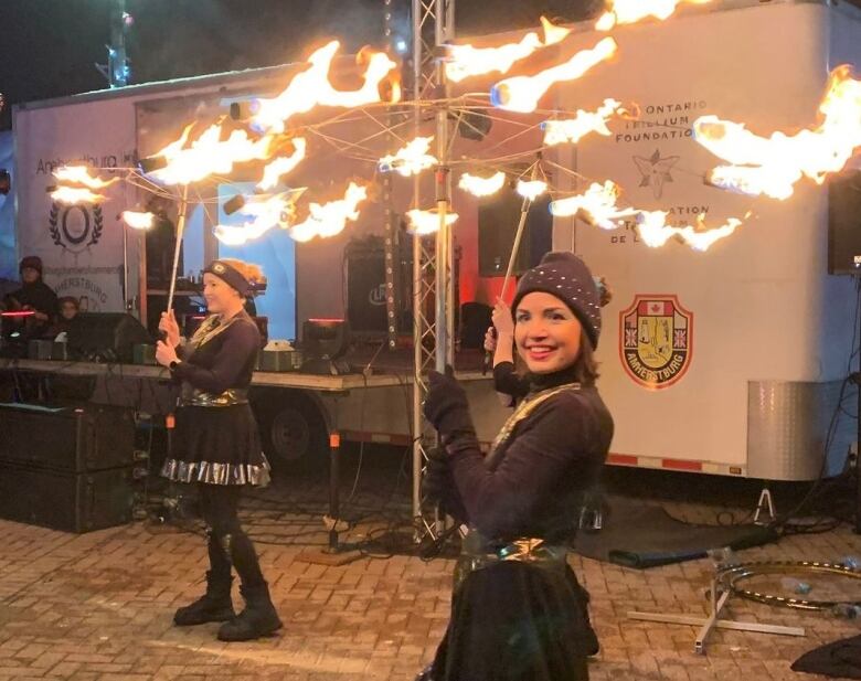 Outdoor fire entertainers perform with flaming items.