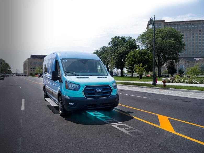 A Ford electric vehicle is shown travelling on an electrified road to charge it.