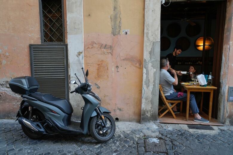 A waiter pours a glass of wine to people dining at a restaurant in downtown Rome, Italy.