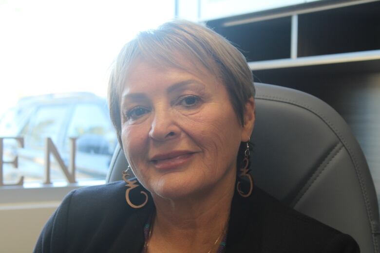 An Indigenous woman in a chair in her office. 