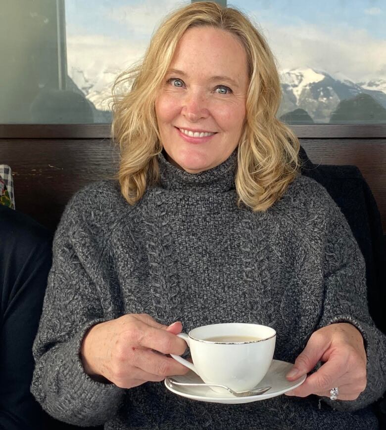 A woman holds a cup of coffee. 