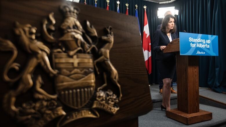 A woman stands behind a podium that reads 