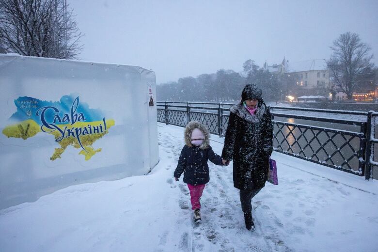 A woman and child walk near the edge of the Uzh river in Uzhhorod, Ukraine.