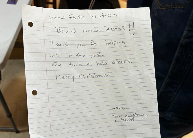 A piece of paper has this handwritten message: Snowflake Station Brand new items. Thank you for helping us in the past. Our turn to help others. Merry Christmas! Love, Your neighbours in town.