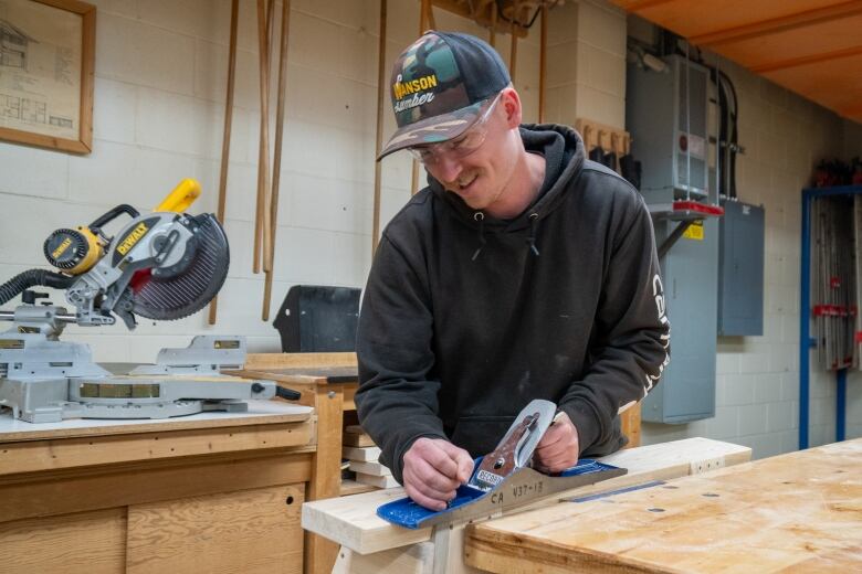 A person planes a piece of wood.