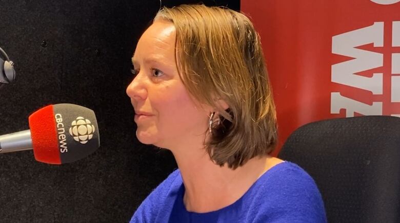 Woman speaking into microphone with a CBC wind sock on it