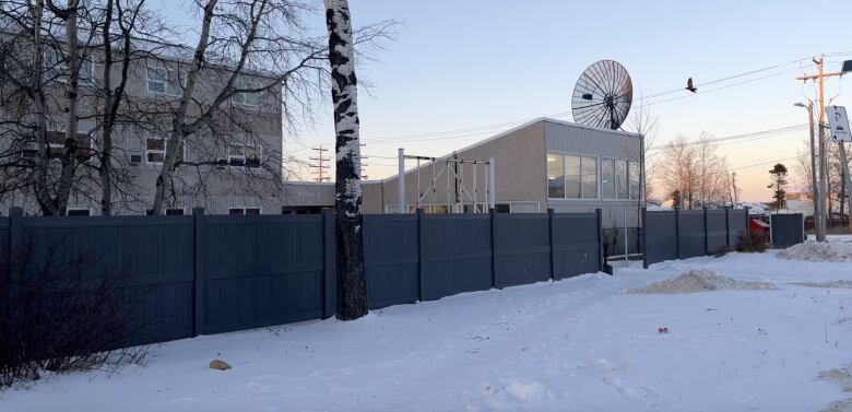 A fence surrounds a three story building.